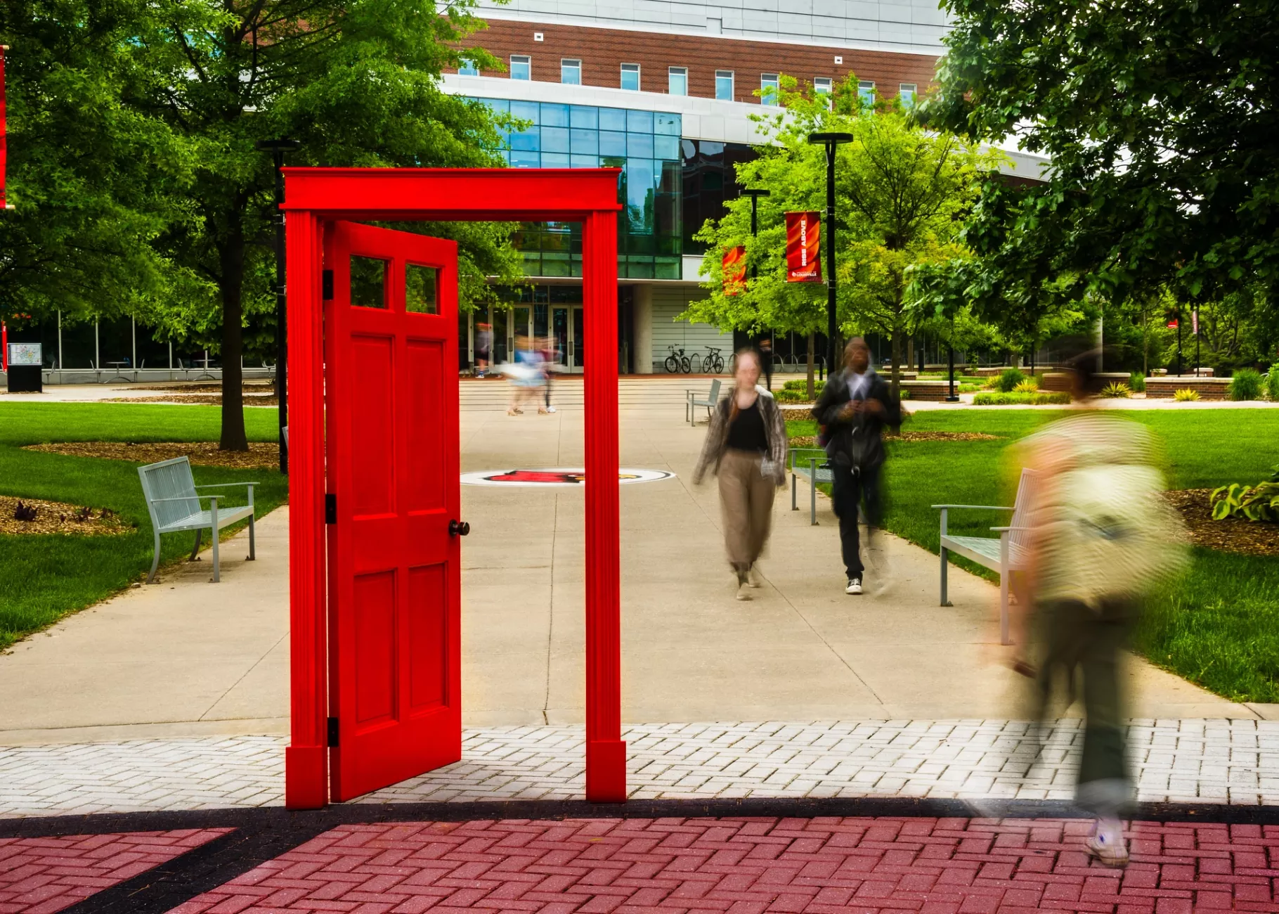 A red doorway on campus with students and an academic building