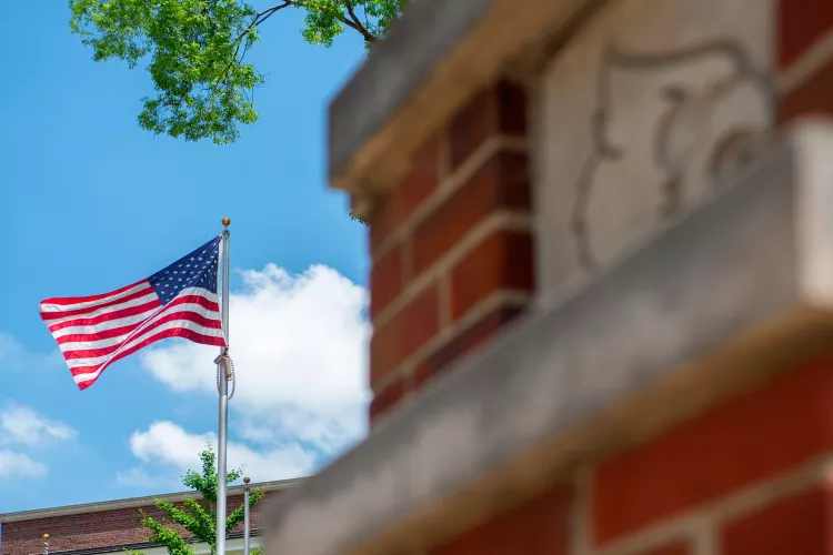 American flag waving in the wind on Belknap Campus