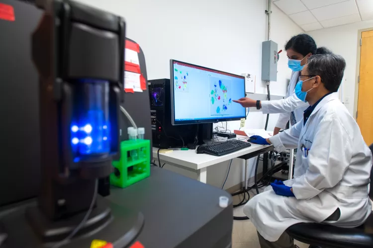Kavitha Yaddanapuddi, Ph.D., and Chuanlin Ding, Ph.D., use a mass cytometer to help improve the effectiveness of cancer immunotherapies.