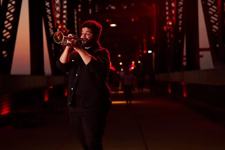 Connor May can be seen playing his trumpet on Big Four Bridge during the sunset.