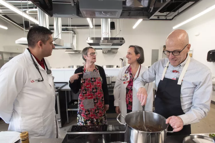 Four adults in a commercial-style kitchen talking