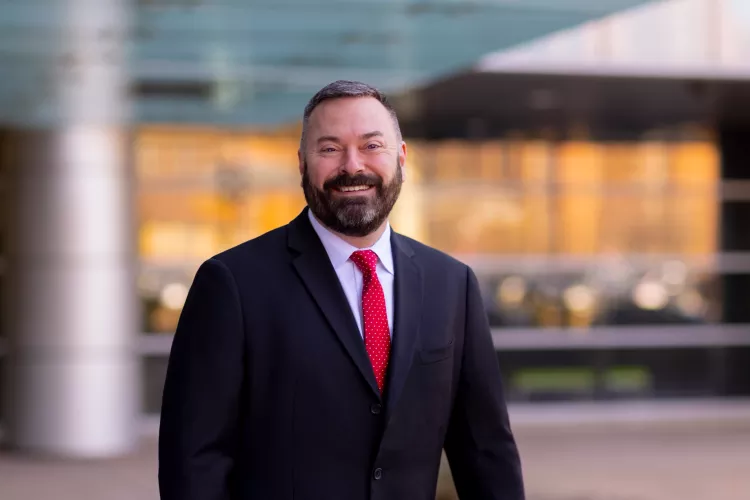 Man with beard in dark suit and red tie