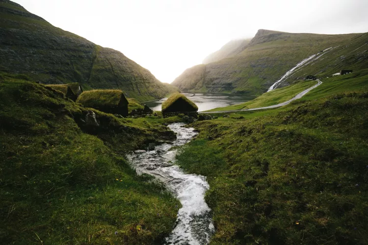 A stream running through a valley with grass huts in Saksun, Faroe Islands