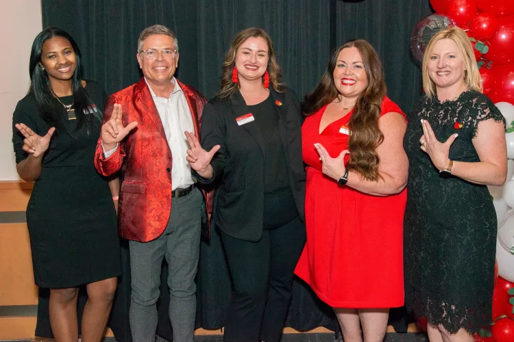 Leaders from UofL's Employee Success Center celebrate together by throwing their L's up., Five leaders from UofL's Employee Success Center throw their L's up in a posed photo.