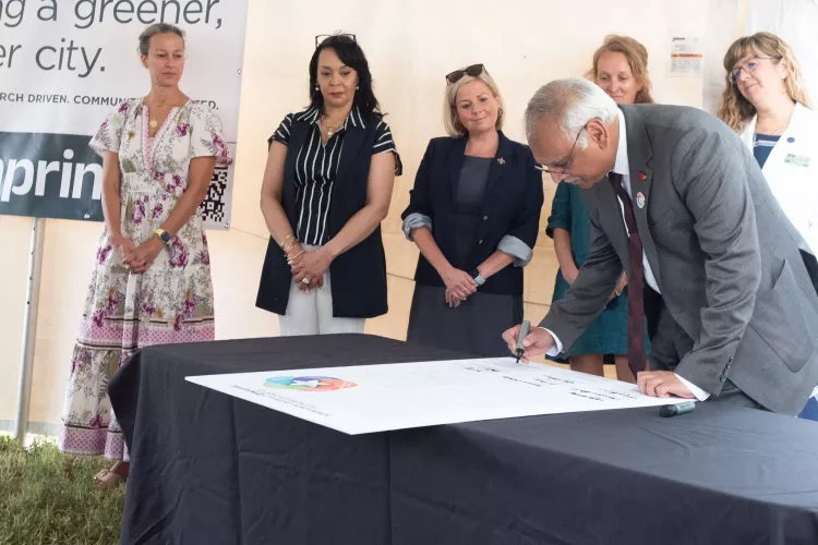 Man signing a large poster on a table.