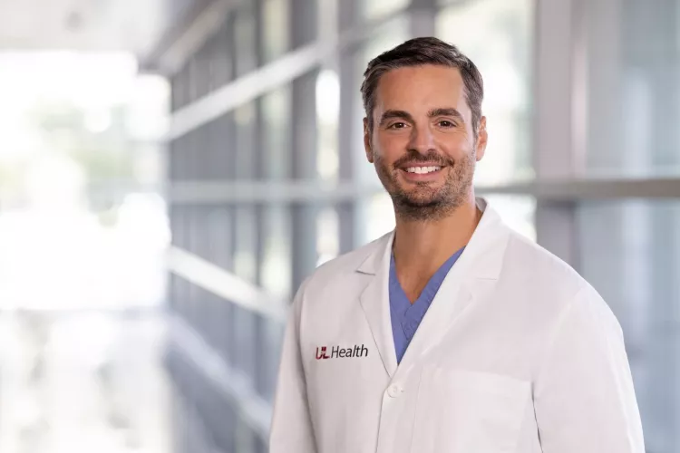 Man in white lab coat with UofL Health insignia