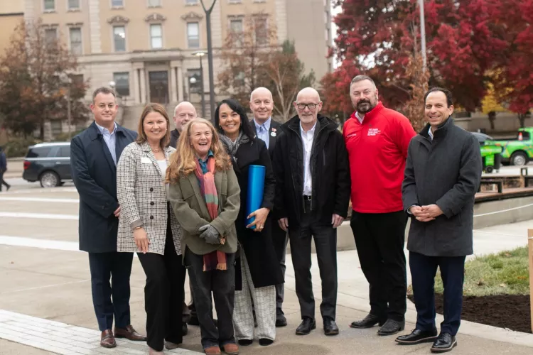 Adults in business attire with trees and buildings in background