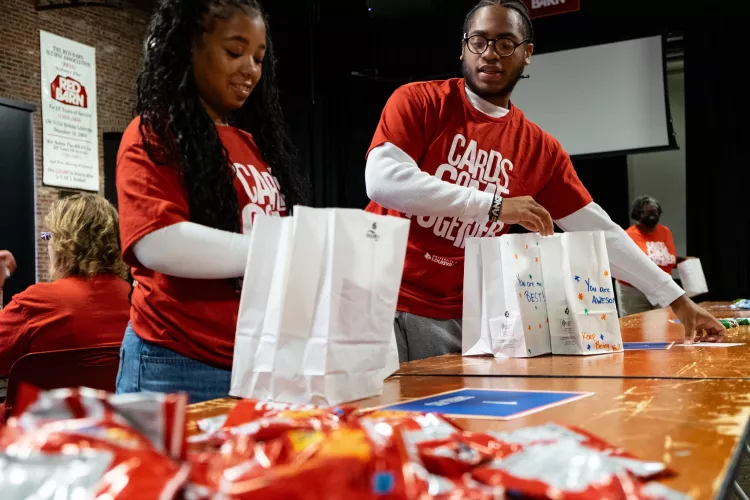 Two people assemble snack bags at the Red Barn.