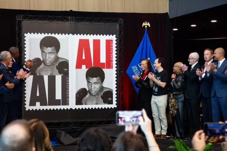 Group of people clapping as Muhammad Ali stamp is unveiled.
