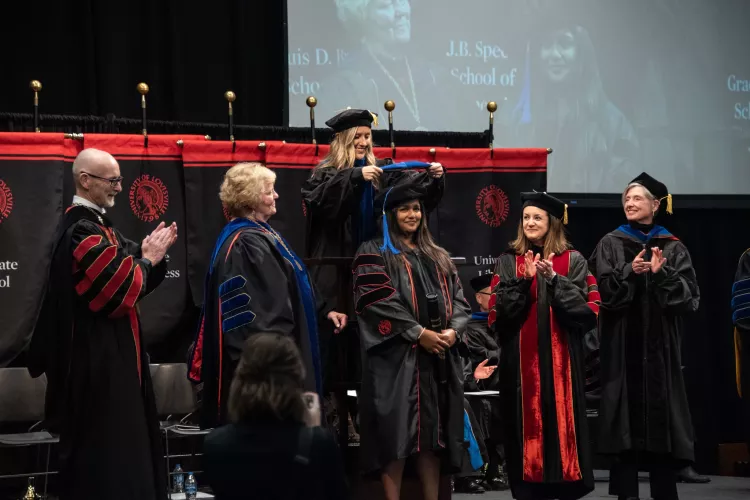 Graduate takes part in ceremonial hooding ceremony.