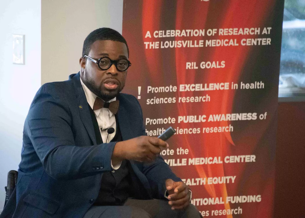 Man seated in front of Research Louisville banner