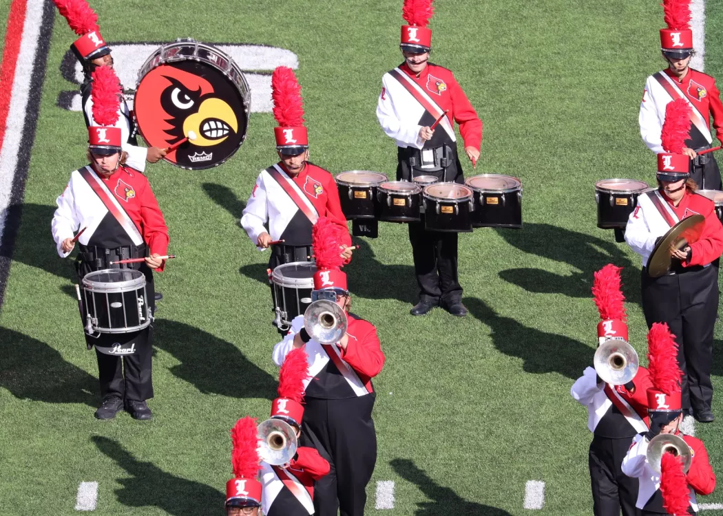 Members of the Marching Cards play instruments at a UofL football game.