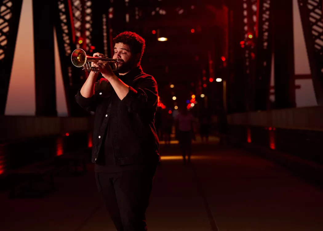 Connor May can be seen playing his trumpet on Big Four Bridge during the sunset.