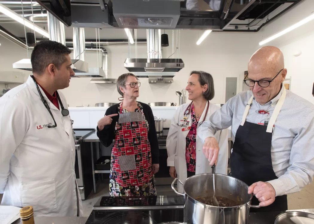 Four adults in a commercial-style kitchen talking