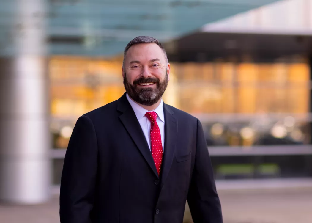 Man with beard in dark suit and red tie
