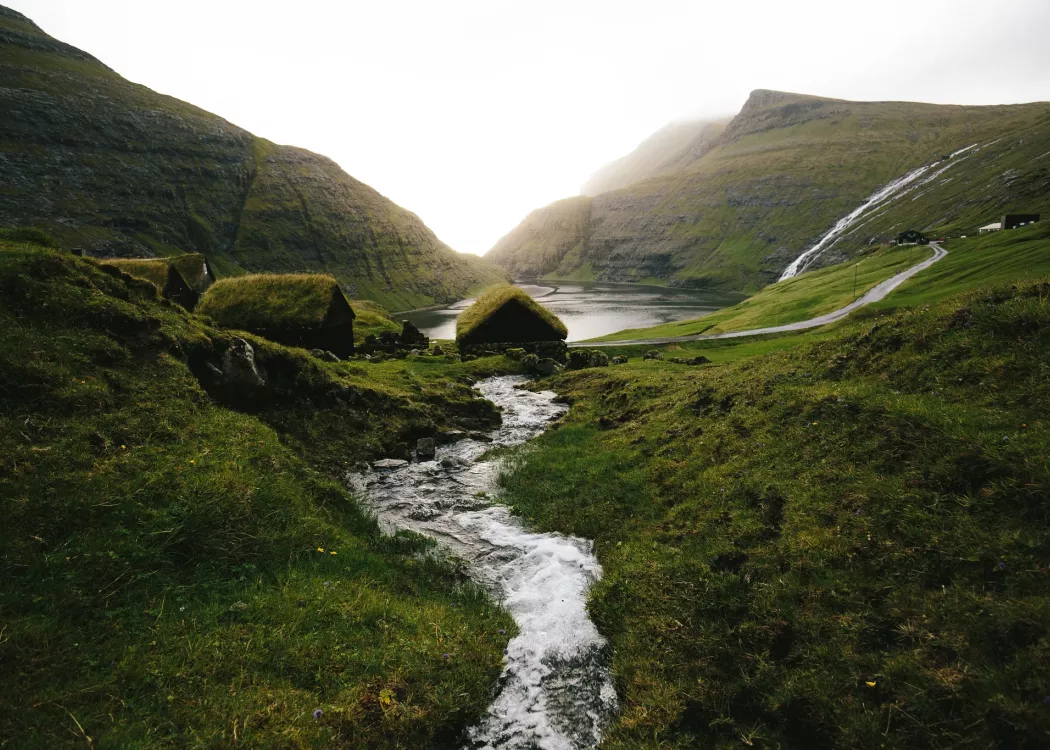 A stream running through a valley with grass huts in Saksun, Faroe Islands