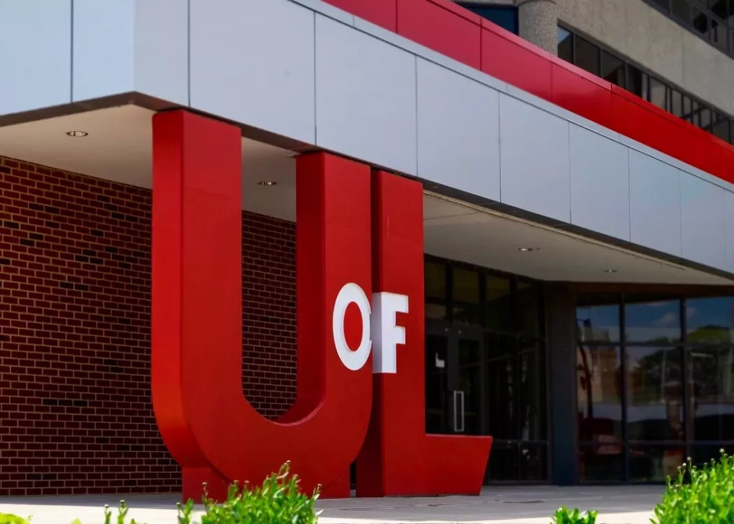 Large UofL logo used as pillars to an overhanging cover outside of a building on campus.
