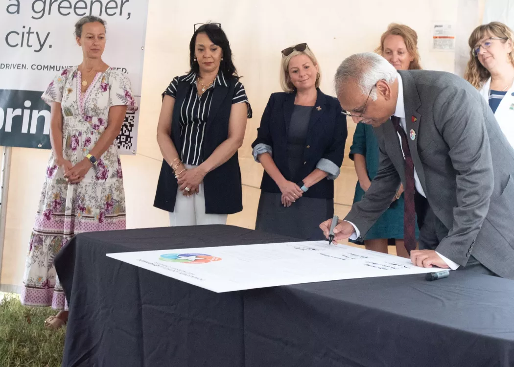 Man signing a large poster on a table.