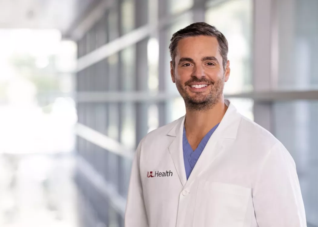 Man in white lab coat with UofL Health insignia