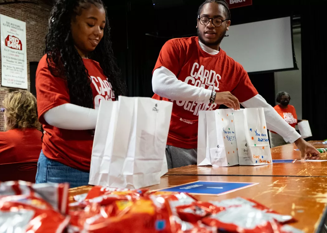 Two people assemble snack bags at the Red Barn.