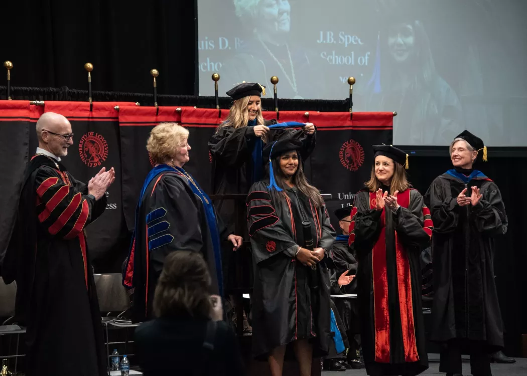 Graduate takes part in ceremonial hooding ceremony.
