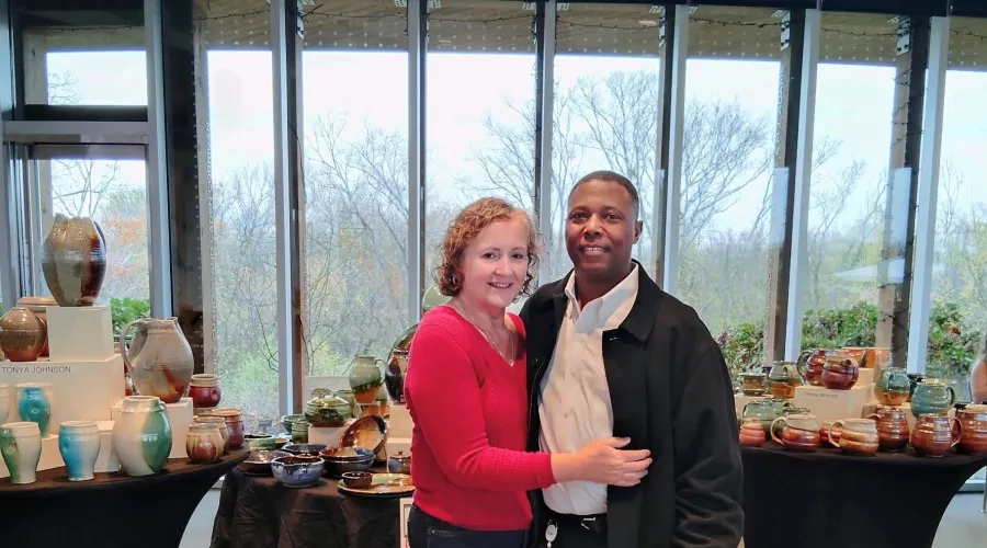 A photo of Tonya Johnson and her partner standing in front of her pottery