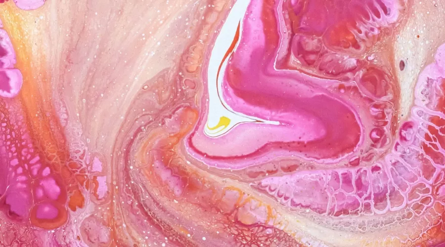 Close-up of the liquid swirls of a pink and yellow fluid painting.