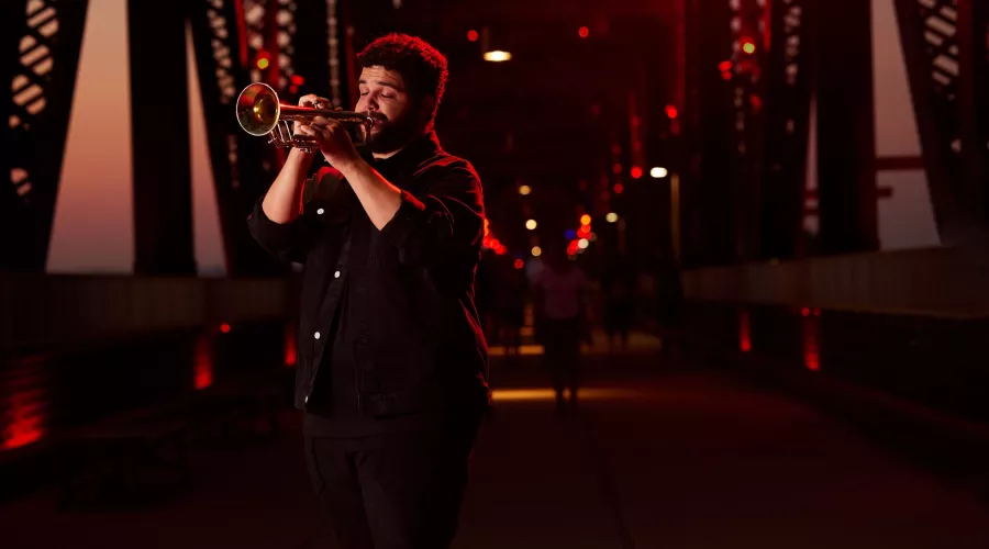 Connor May can be seen playing his trumpet on Big Four Bridge during the sunset.
