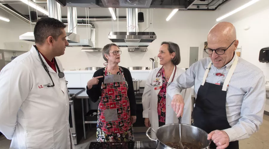 Four adults in a commercial-style kitchen talking