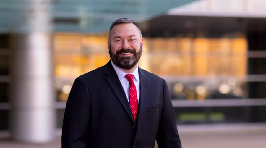 Man with beard in dark suit and red tie