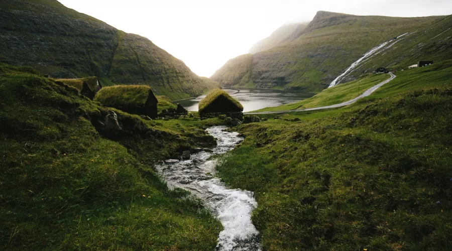 A stream running through a valley with grass huts in Saksun, Faroe Islands
