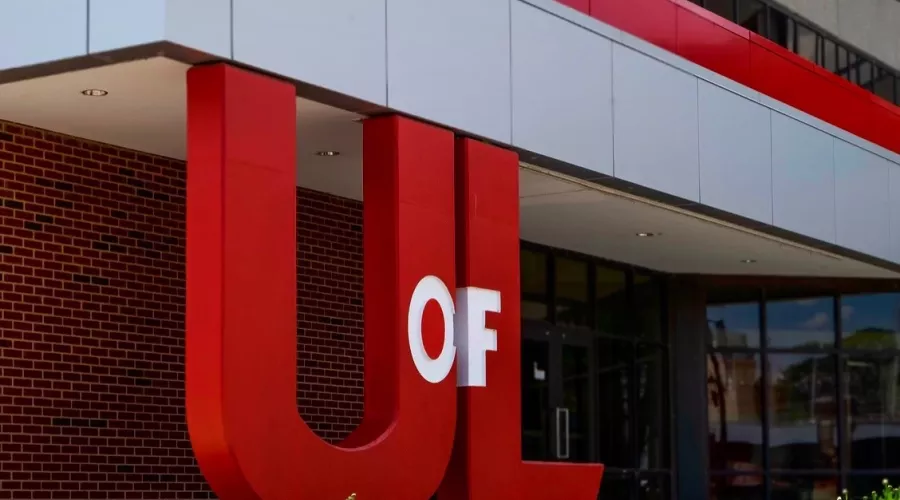 Large UofL logo used as pillars to an overhanging cover outside of a building on campus.