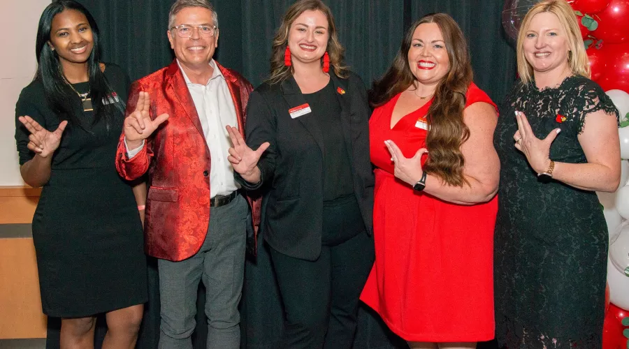 Leaders from UofL's Employee Success Center celebrate together by throwing their L's up., Five leaders from UofL's Employee Success Center throw their L's up in a posed photo.