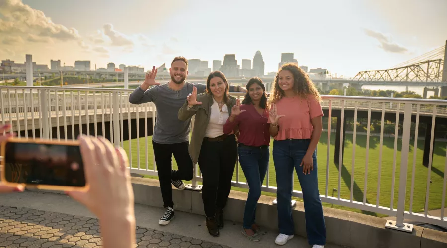 Students throwing up their L's for a group photo opportunity at the Big Four Bridge at Waterfront Park in downtown…