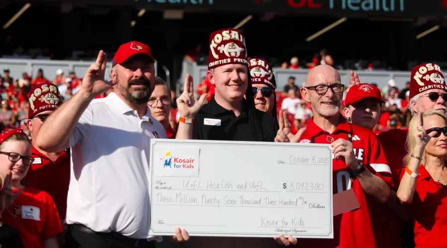 Gerry Bradley and Jason Smith hold a Kosair for Kids check at the Oct. 4 UofL football game.