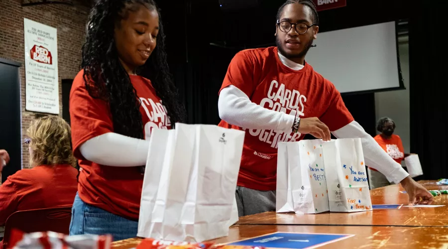 Two people assemble snack bags at the Red Barn.