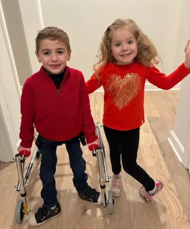Two children dressed in red standing in a hallway