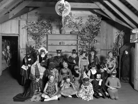 A black and white photograph of a group of children dressed in Halloween costumes wearing masks in 1928.