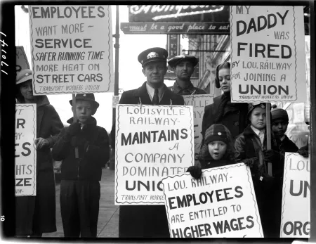 A black and white photo from 1939 showing a Louisville union workers and families holding demonstration signs.