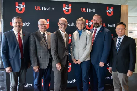 Six adults standing in front of UofL Health backdrop