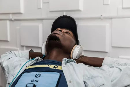 A man wearing white headphones leaning back and relaxing.