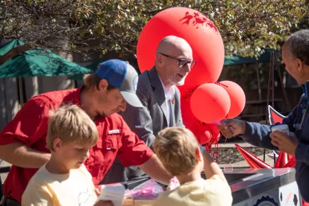UofL President Gerry Bradley outside at an ice cream cart, talking to patrons.