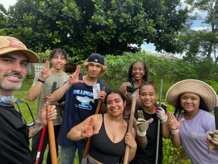 A group of students with UofL hand signals in a Puerto Rican park.