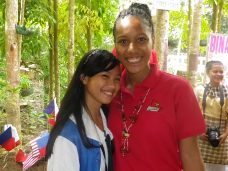 Two young women pose for a photograph in a tropical Philippines setting.