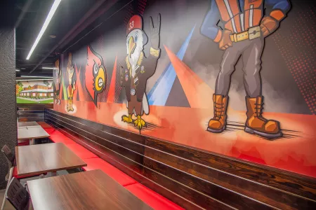 UofL Cardinal Bird head and Texas Roadhouse characters with tables and seats